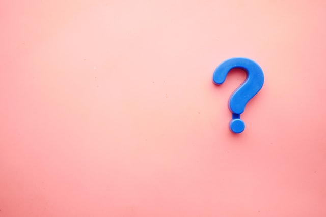 Blue question mark against a light pink background 