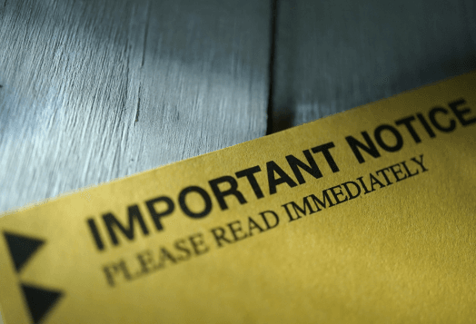 A close-up of a yellow document with "IMPORTANT NOTICE PLEASE READ IMMEDIATELY" printed in black
