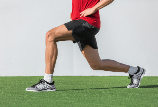 Man lunging on green turf, white wall