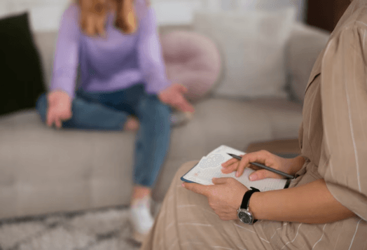 Therapist taking notes while patient talks on a couch